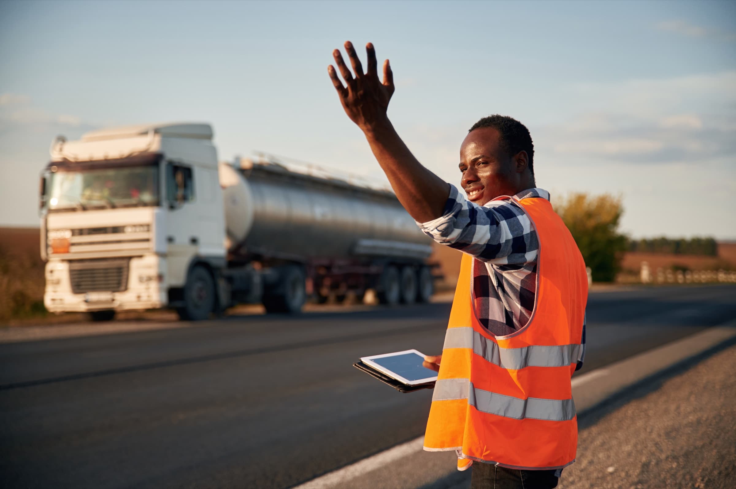 A Gasability driver waving beside a tanker truck at golden hour